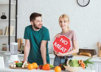 couple of vegans standing with no meat sign at kitchen