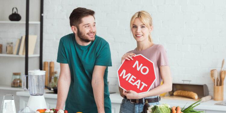 couple of vegans standing with no meat sign at kitchen