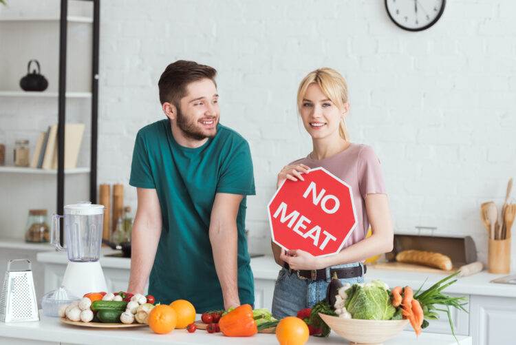 couple of vegans standing with no meat sign at kitchen